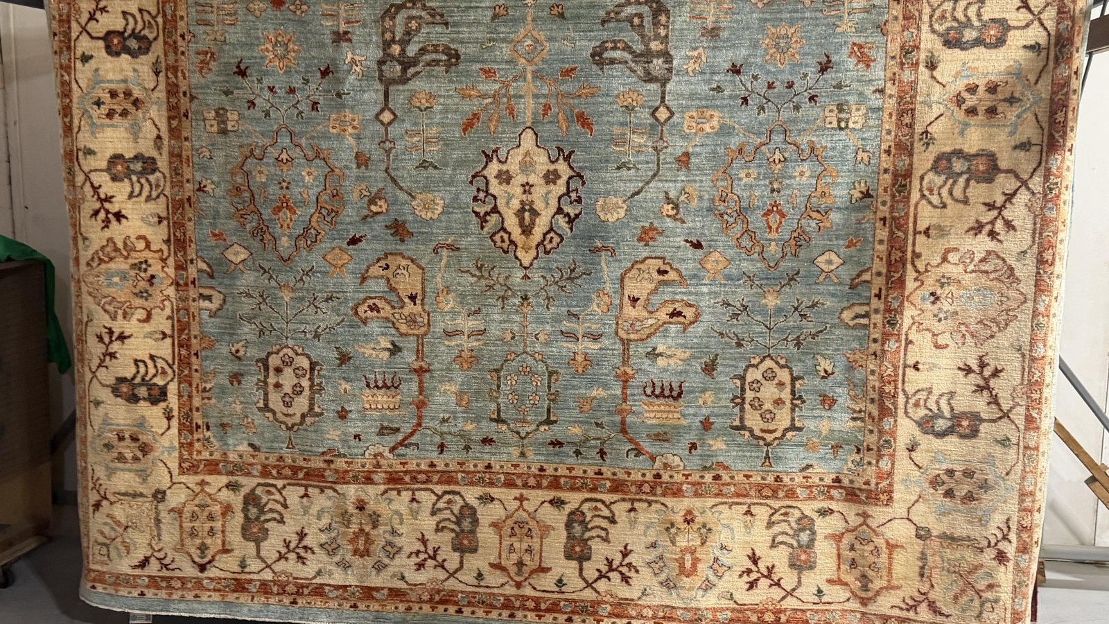A wool rug hanging on the rack with rinse water running clear off the pile